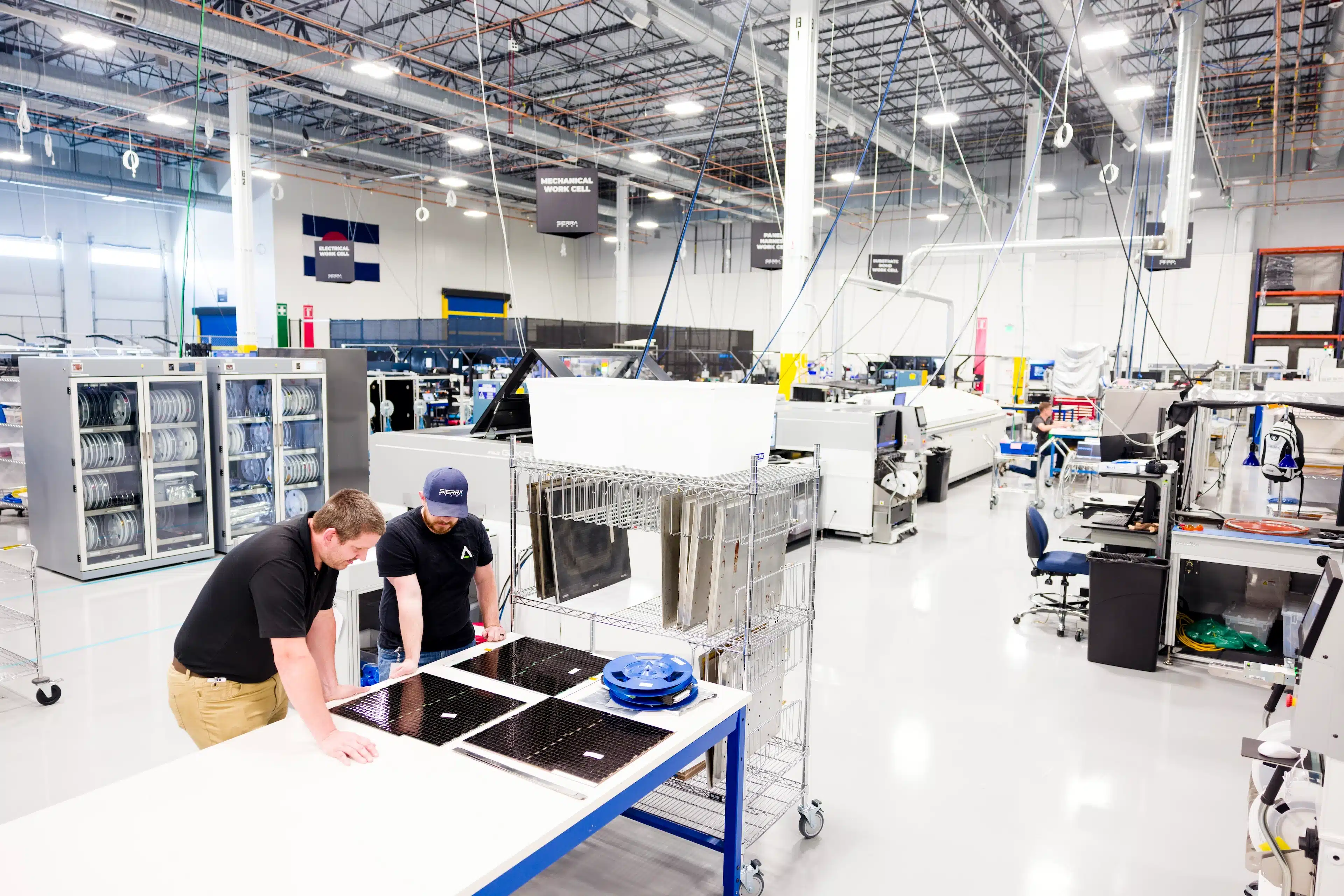Two Sierra Space team members working together at a solar-hardware worktable